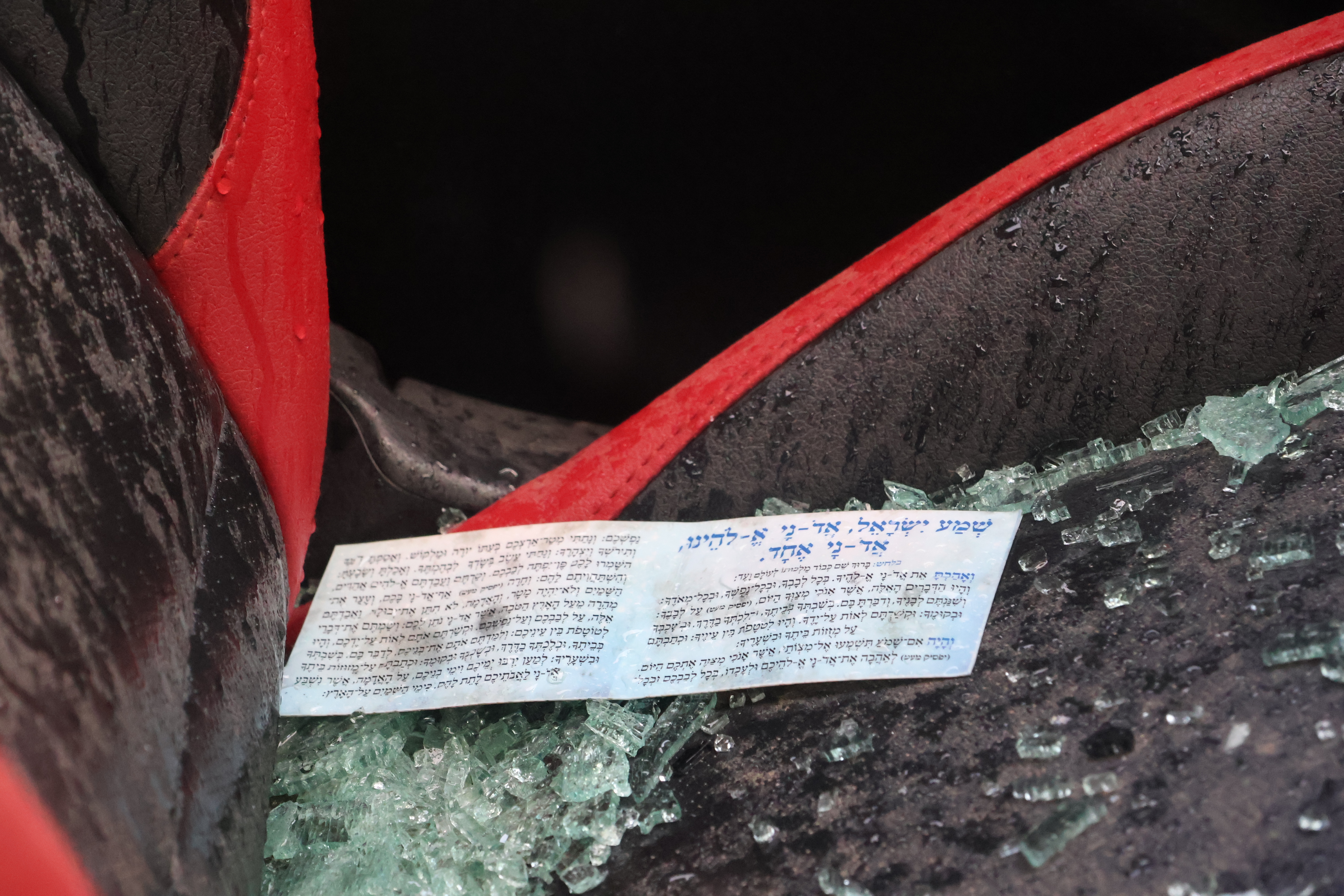 A card with the words of Shema sits on the seat of a car destroyed on October 7